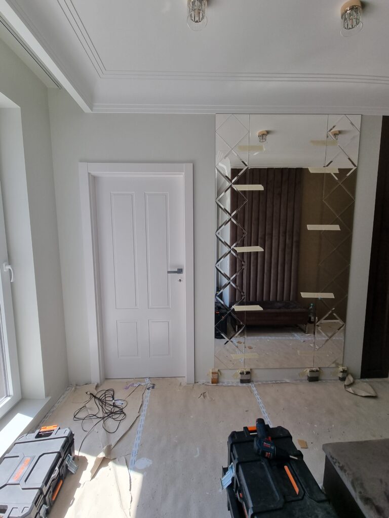 Montaż lustra w holu, jeszcze zabezpieczonego taśmą, apartament 90m², SM STUDIO